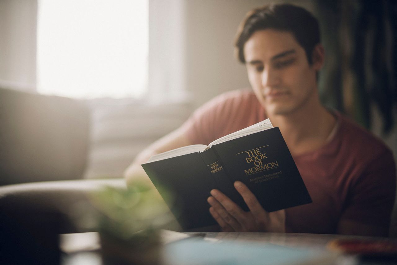 Muž studuje Knihu Mormonovu u kuchyňského stolu