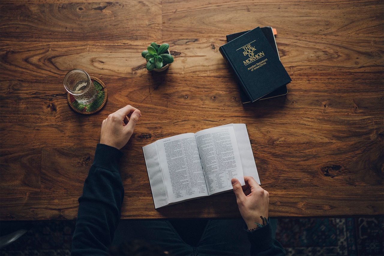Muž studuje u kuchyňského stolu Bibli a Knihu Mormonovu