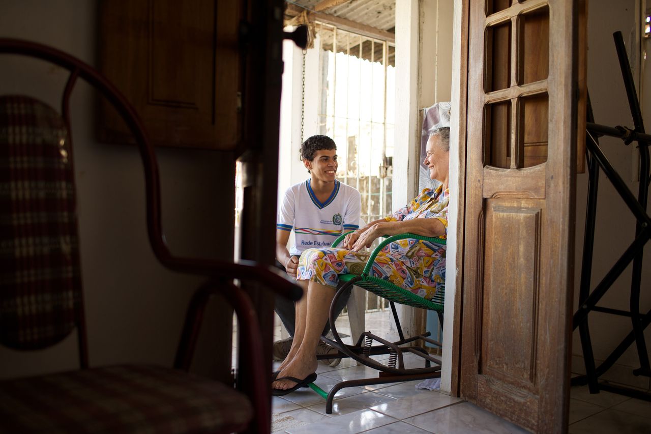 Mladý muž sedí na verandě se starší ženou při návštěvě, kdy se společně těší z evangelia Ježíše Krista